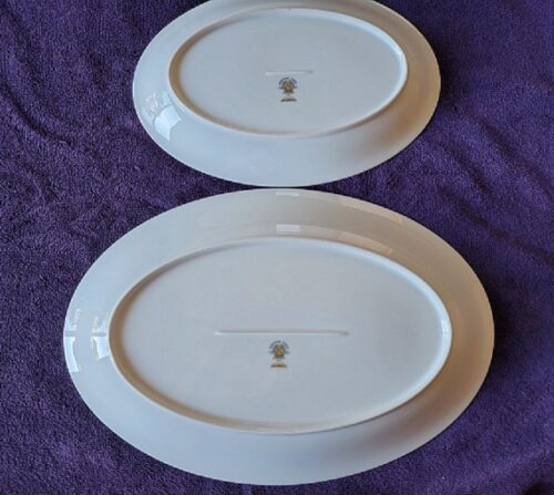 Two white plates with a gold design on them.