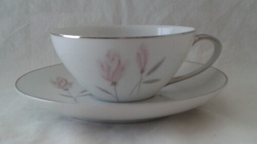 A white cup and saucer with pink flowers on it.