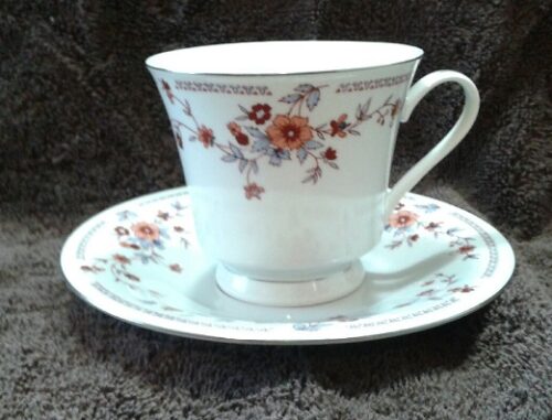A white cup and saucer with flowers on it.