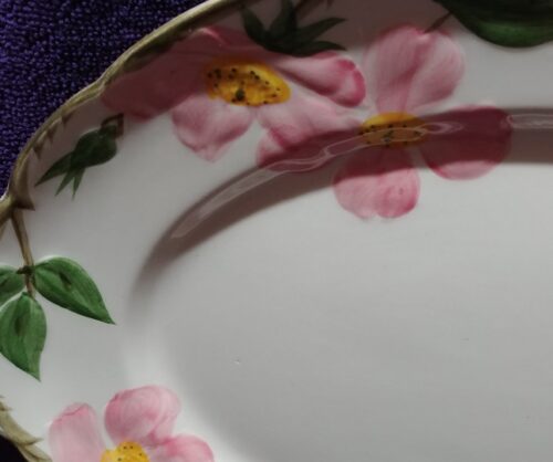 A close up of the edge of a plate with pink flowers