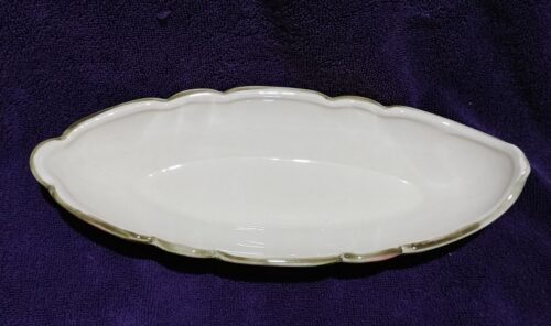 A white dish with gold trim on purple cloth.