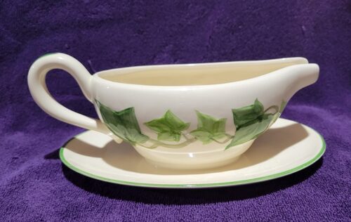 A white gravy boat with green ivy on it.