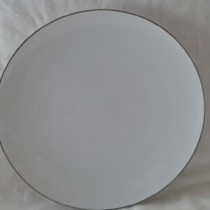 A white plate with black rim on top of a table.