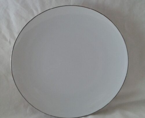 A white plate with black rim on top of a table.