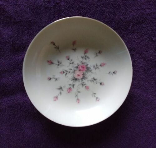 A white bowl with pink flowers on it.