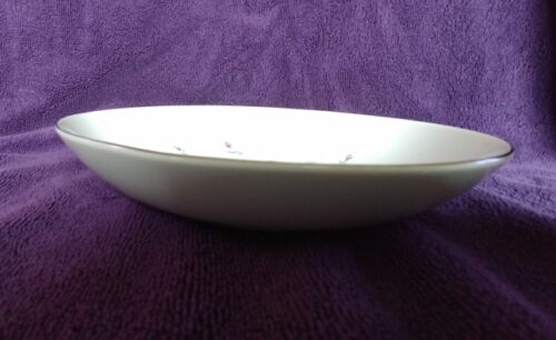 A white bowl sitting on top of purple cloth.