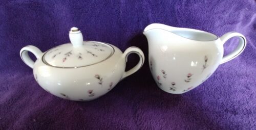 A white tea pot and cup on purple background.