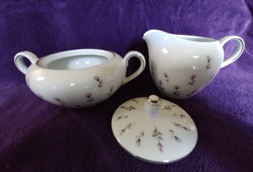 A white tea set with purple flowers on it.