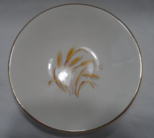 A white bowl with gold trim and some brown flowers