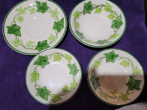 Four bowls with green ivy on them are sitting on a purple table.