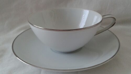 A white cup and saucer with silver trim.