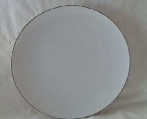 A white plate with a black rim on top of a table.