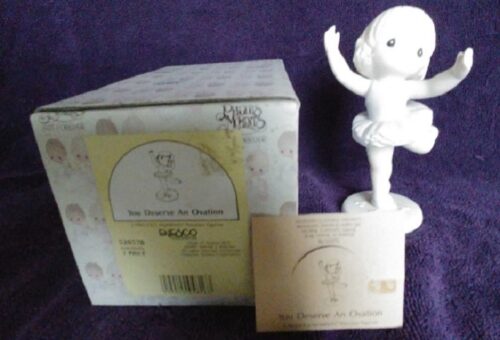A white figurine is sitting in front of the box.