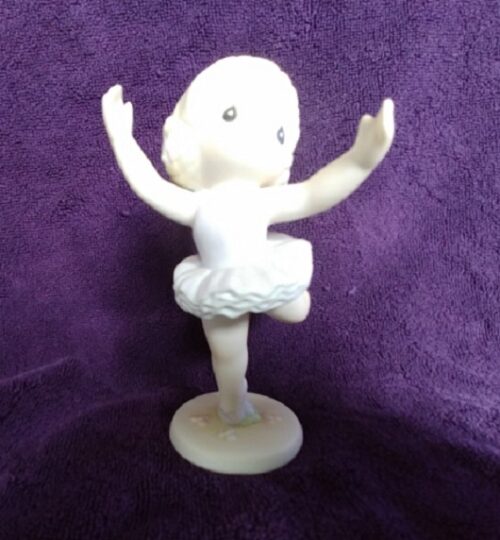 A white figurine of a girl in a tutu.