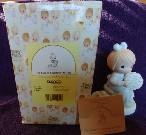 A baby figurine and its box are next to a card.