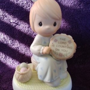 A figurine of a girl holding a basket and a wooden disc.