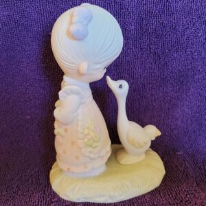 A figurine of a woman and goose on purple background.