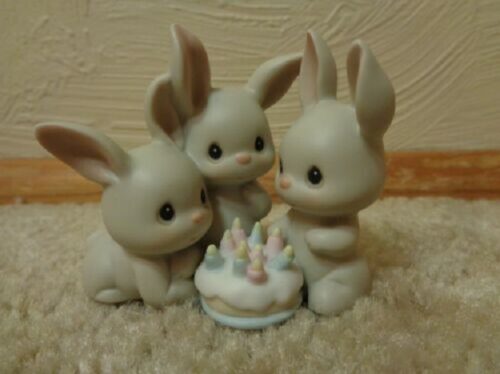 Three bunnies are sitting next to a cake.