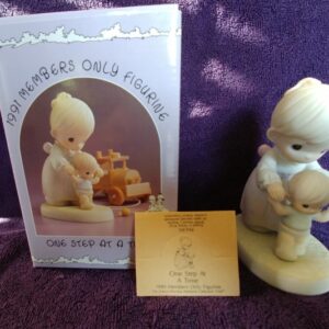 A baby figurine and a note sitting on top of the box.