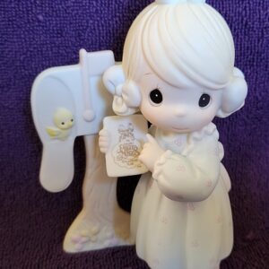 A white figurine of a girl holding a card.
