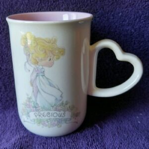 A cup with a heart shaped handle and a picture of a girl.