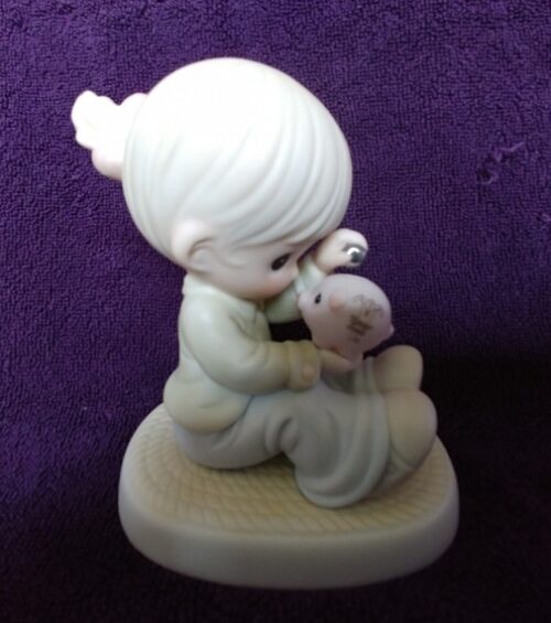 A figurine of a boy holding a stuffed animal.