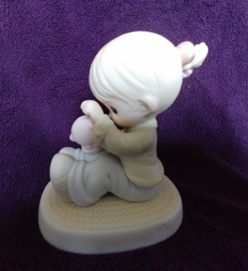 A figurine of a girl kneeling down with her hands in the air.