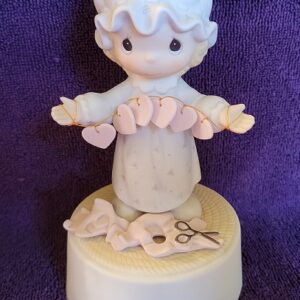A figurine of a person holding scissors and sewing machine.