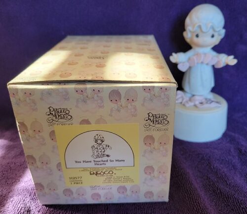A box and figurine of a baby sitting on the ground.
