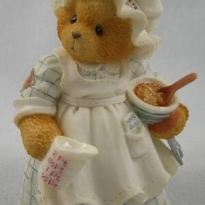 A teddy bear dressed as a woman holding a bowl.