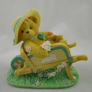 A yellow teddy bear in a wheel barrow.