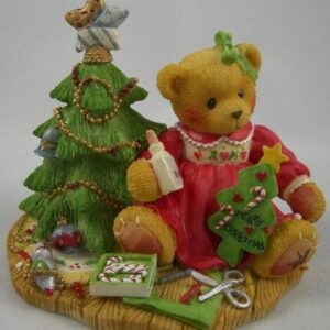 A teddy bear sitting next to a christmas tree.