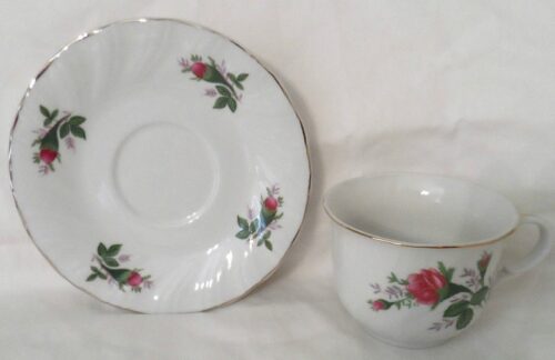 A white plate and cup with red roses on it.