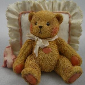 A teddy bear sitting on top of a pillow.