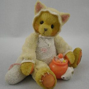 A teddy bear wearing an apron and holding a pot.