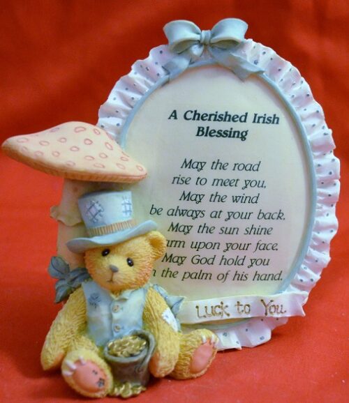 A teddy bear wearing a hat and holding a picture frame.