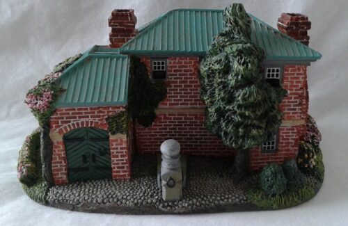 A toy house with trees and bushes on the side.