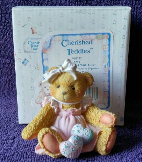 A teddy bear in pink dress with white bow.