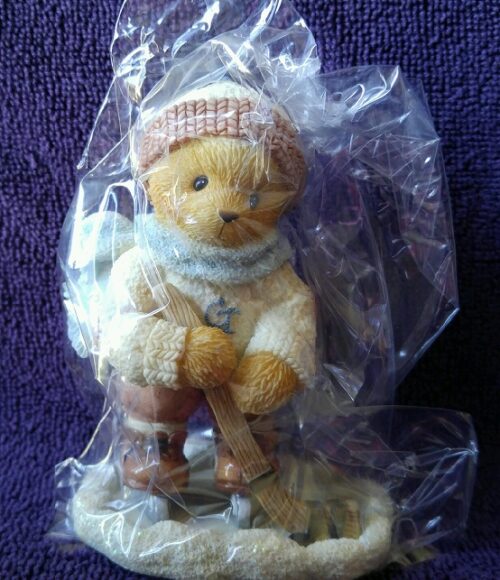 A teddy bear wearing a hat and holding a baseball bat.