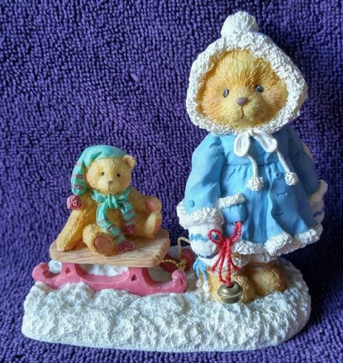 A teddy bear and a girl on a sled.