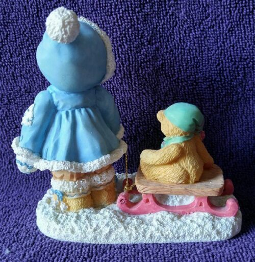 A figurine of a girl and bear on a sled.