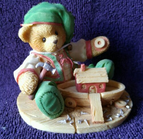 A teddy bear sitting on top of a wooden block.