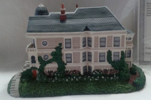 A model of a house with bushes and trees.