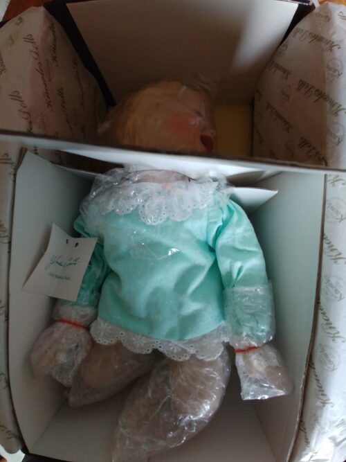 A doll in a box with its head hanging down.