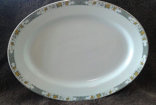 A white plate with gold and blue trim on top of the table.