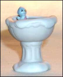 A small ceramic bird in the middle of a sink.