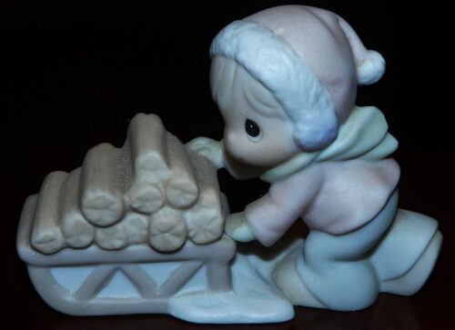 A figurine of a baby in a sled with logs.