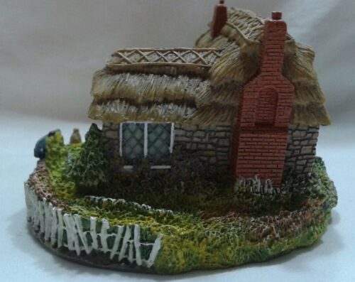 A small house with a thatched roof and grass on the front.