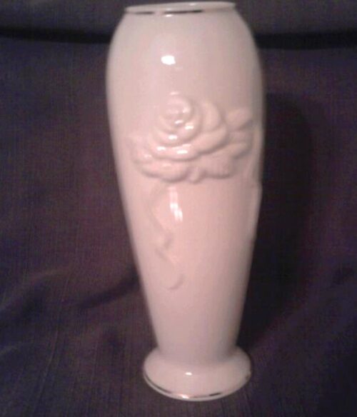 A white vase with a rose on it.