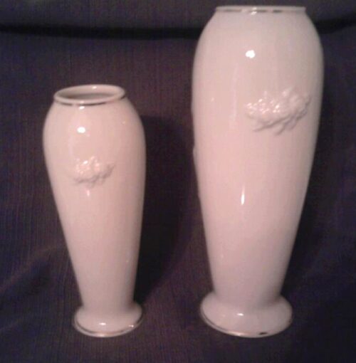 Two white vases with a flower design on the side.